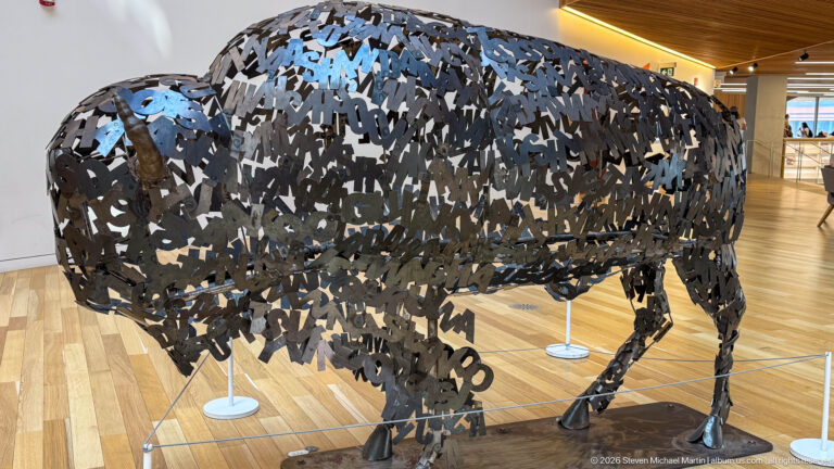 Side view of Lionel Peyachew’s Education is the New Buffalo, built from overlapping dark metal letters.