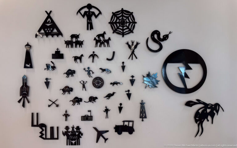 Adrian Stimson’s Art as Language installation of Blackfoot pictographic symbols across a white wall at Calgary Central Library.