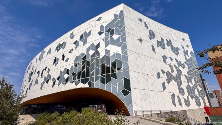 Calgary Central Library exterior with white geometric cladding, irregular dark windows, and deep wood-lined arch.