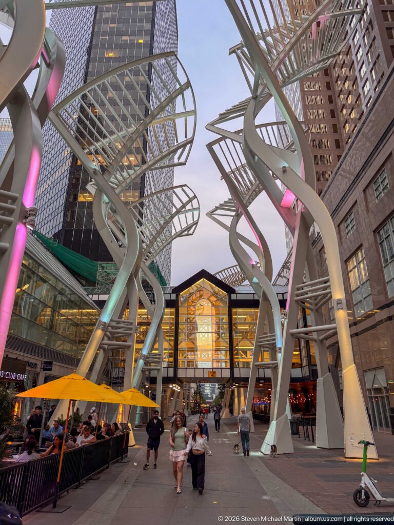 Illuminated Galleria Trees above pedestrians, restaurant patios, and yellow umbrellas on Stephen Avenue in Calgary.