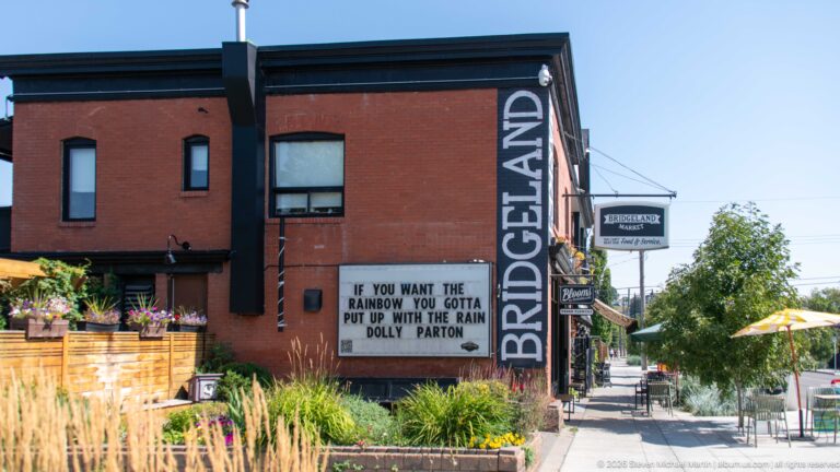Red-brick Bridgeland restaurant with vertical signage and a marquee quoting Dolly Parton about rainbows and rain.