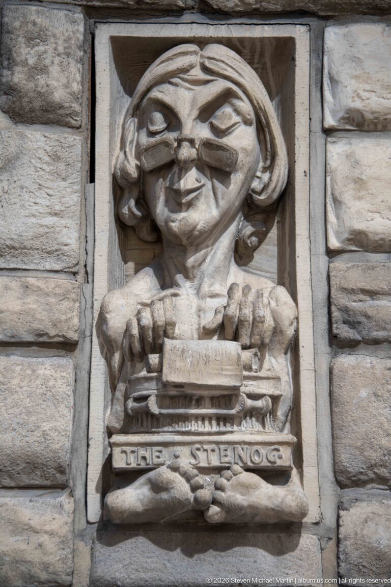 Stone relief labeled The Steno, showing a bespectacled woman posed with a small office machine.