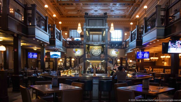 Central bar beneath a large clock in the ornate former banking hall of the Bank & Baron pub.