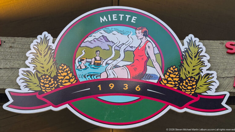 Circular Miette emblem with stylized bathers, mountains, foliage, pinecones, and the date 1936.