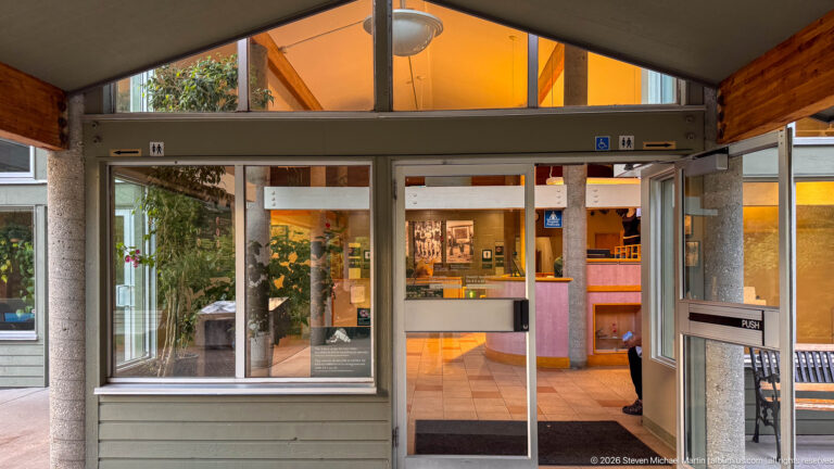 Glass sliding entrance doors opening into the illuminated Miette Hot Springs reception area with counters and displays.