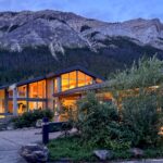 Miette Hot Springs building glowing at dusk beneath steep gray mountain cliffs and conifer forest.