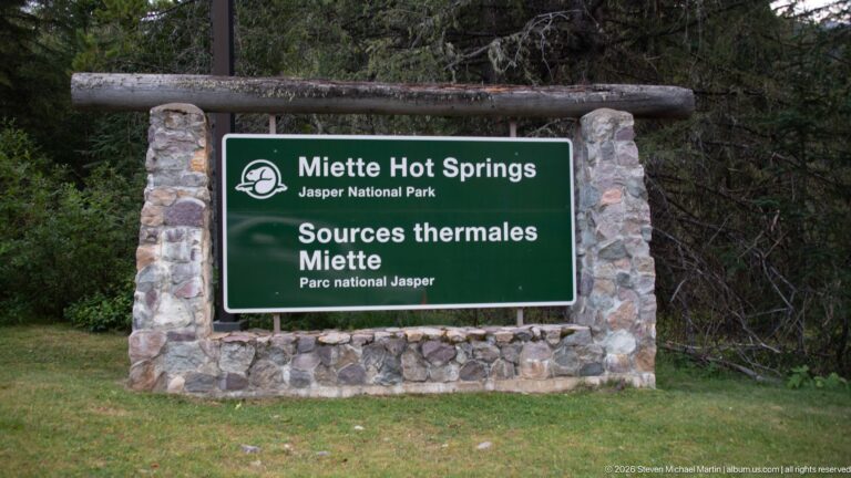 Stone-framed green sign reading Miette Hot Springs, Jasper National Park, and Sources thermales Miette.
