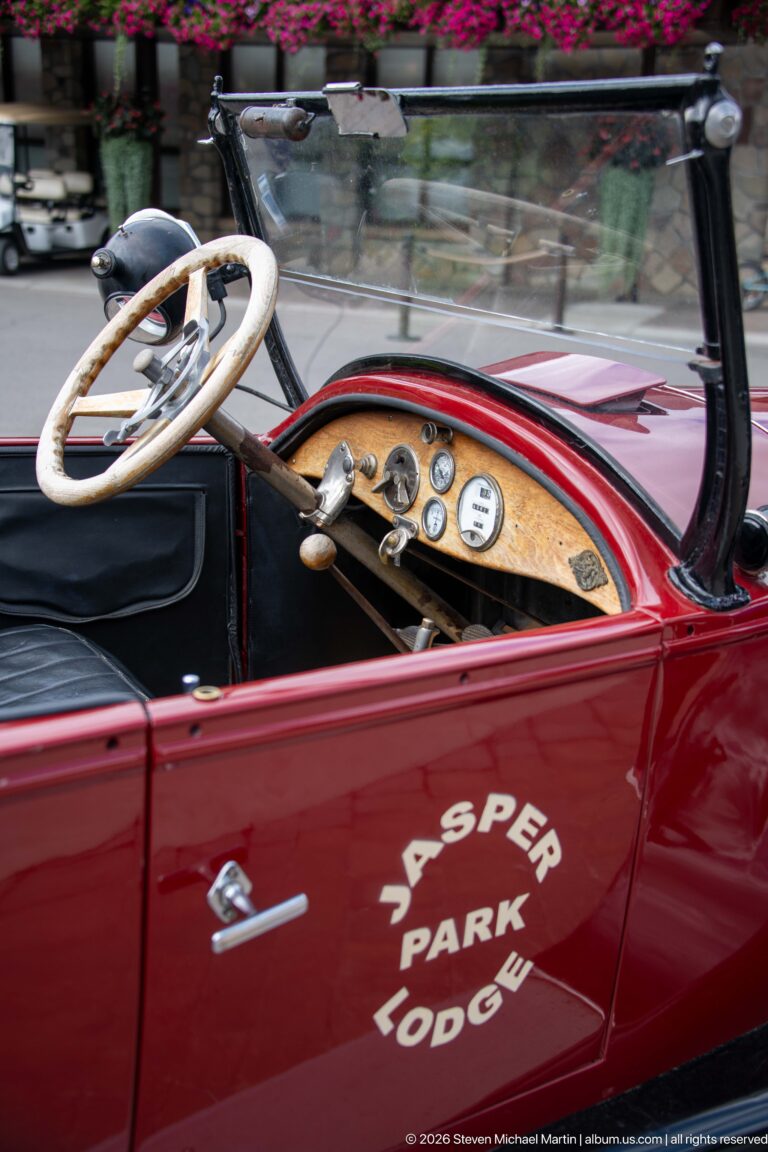 Burgundy open touring car with Jasper Park Lodge lettering, pale steering wheel, and wood dashboard.