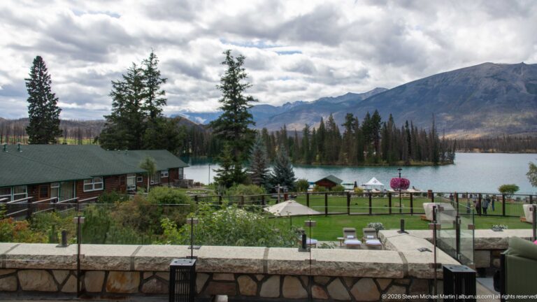 Elevated view over lodge cabins and landscaped grounds toward Lac Beauvert and mountains.