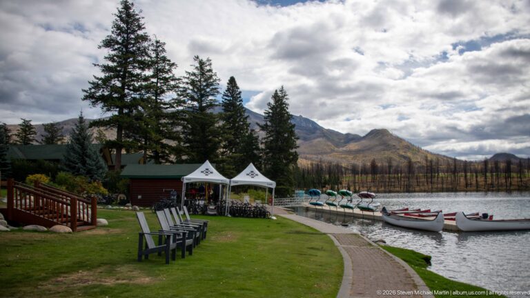 Canoes, waterfront chairs, and white tents along the grassy shore of Lac Beauvert.