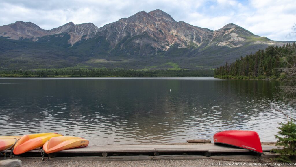 Orange and red paddlecraft along the shore of Pyramid Lake with a rugged mountain across the water.