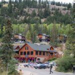 Rustic wood lodge buildings among trees above a road and parked cars near Pyramid Lake.