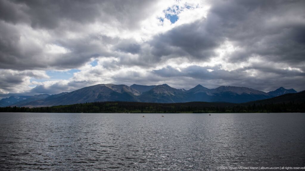 Wide view across rippled Pyramid Lake toward a dark mountain range beneath heavy storm clouds.
