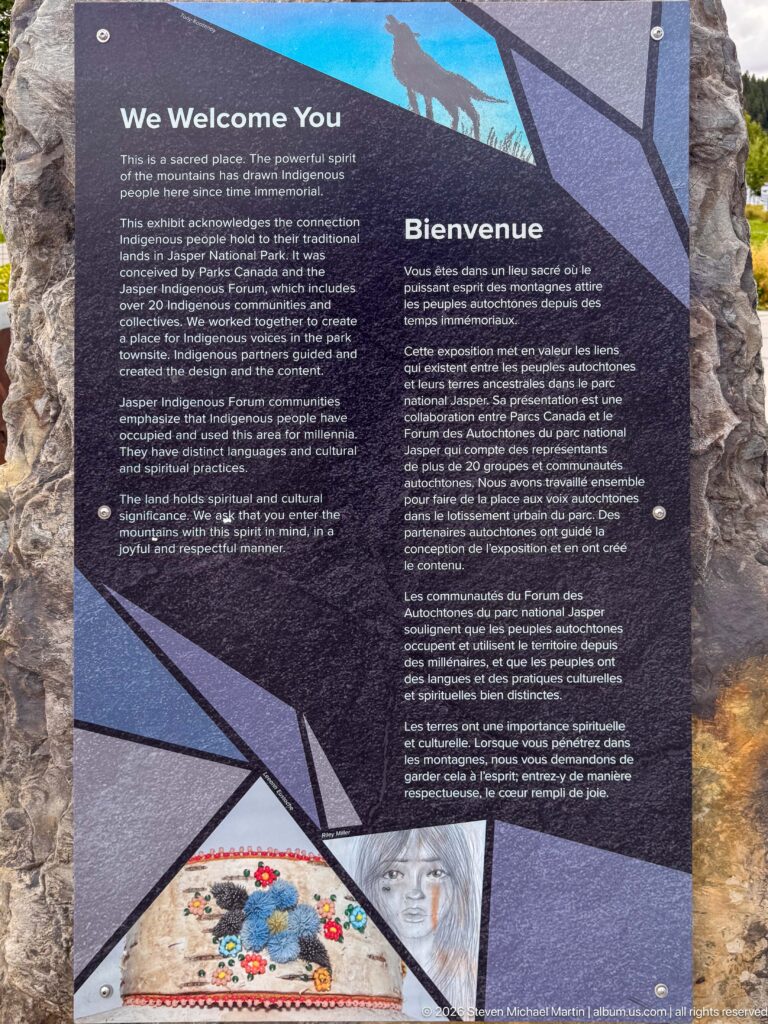 Dark bilingual interpretive panel with Indigenous welcome text, geometric graphics, an animal silhouette, and a colorful circular motif.