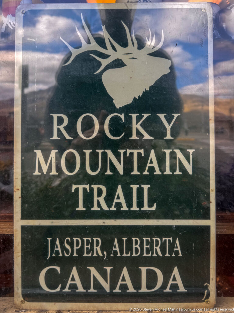 Dark green Rocky Mountain Trail sign with an elk-head emblem and Jasper, Alberta, Canada lettering.