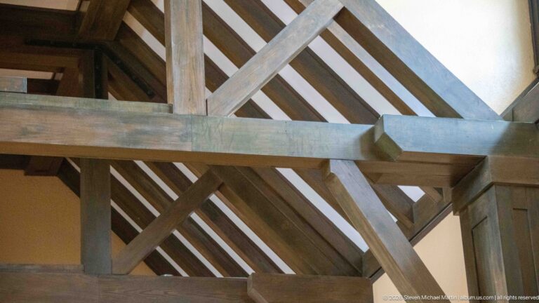 Close architectural detail of heavy timber posts, beams, diagonal braces, and roof rafters inside Jasper railway station.