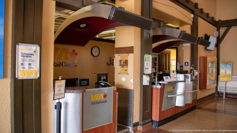 VIA Rail Canada ticket counters beneath curved canopies, with a clock, schedule display, and Jasper station lettering.
