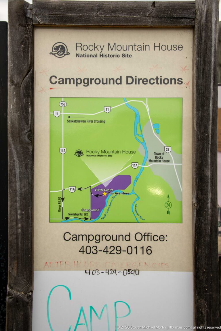 Wood-framed campground directions sign with regional map, highways, route arrows, and campground office phone number.