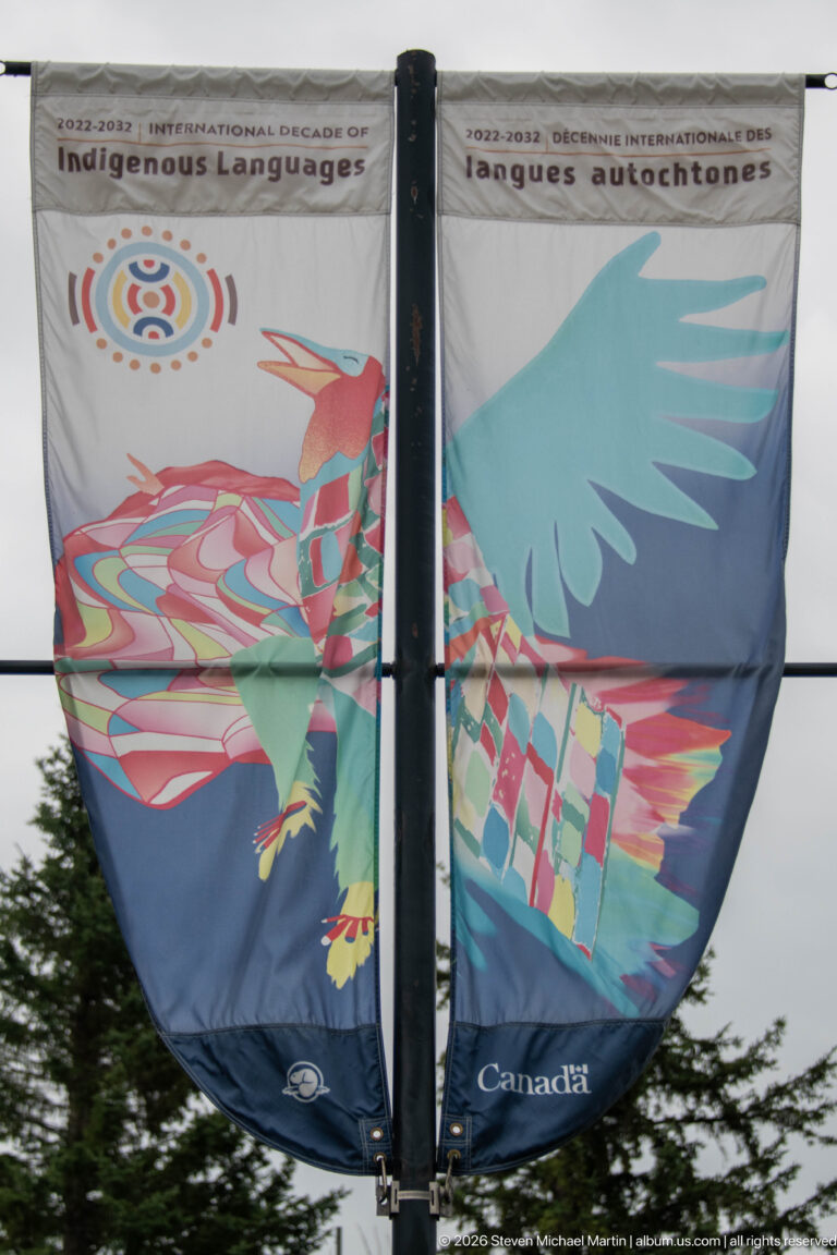 Two-panel Parks Canada banner forming a colorful stylized bird with broad wings and geometric patterned body.