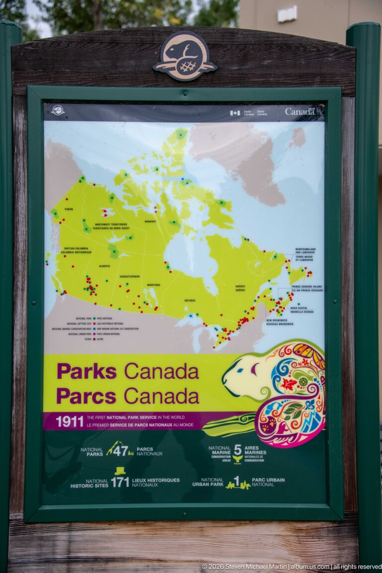 Framed Parks Canada panel with a green map of Canada, site markers, bilingual branding, and colorful anniversary graphic.