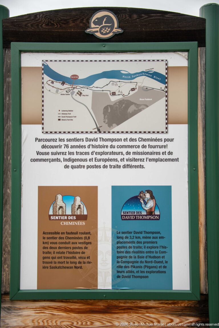 Framed French trail sign with a route map and two illustrated historical figures for the David Thompson and Chimney trails.
