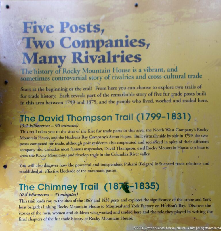 Yellow interpretive panel titled “Two Posts, Two Companies, Many Rivalries” describing the David Thompson and Chimney trails.
