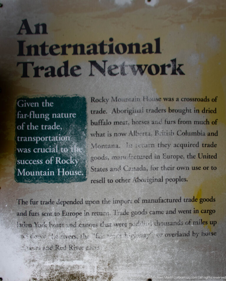Weathered yellow panel titled 'International Trade Network' explaining local Indigenous exchange and imported manufactured trade goods.