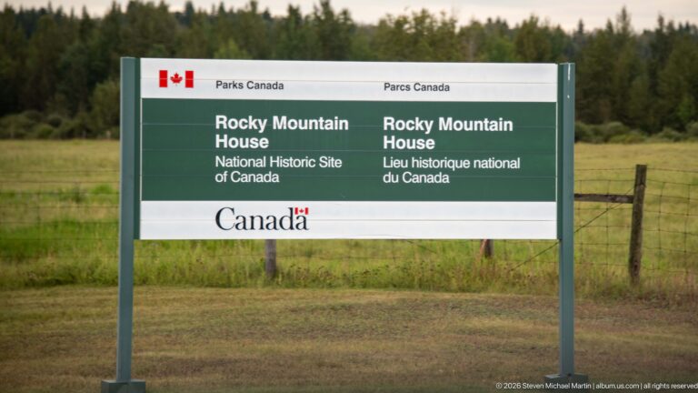 Close view of green-and-white bilingual Parks Canada sign naming Rocky Mountain House National Historic Site.