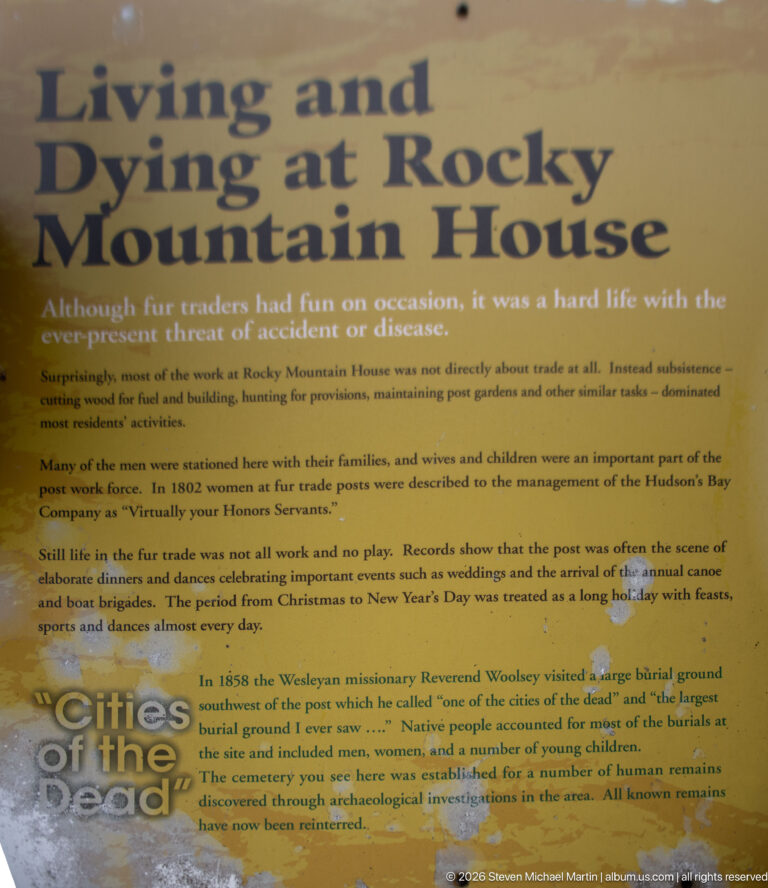 Weathered yellow interpretive panel discussing life, disease, domestic routines, celebrations, and burial at Rocky Mountain House.
