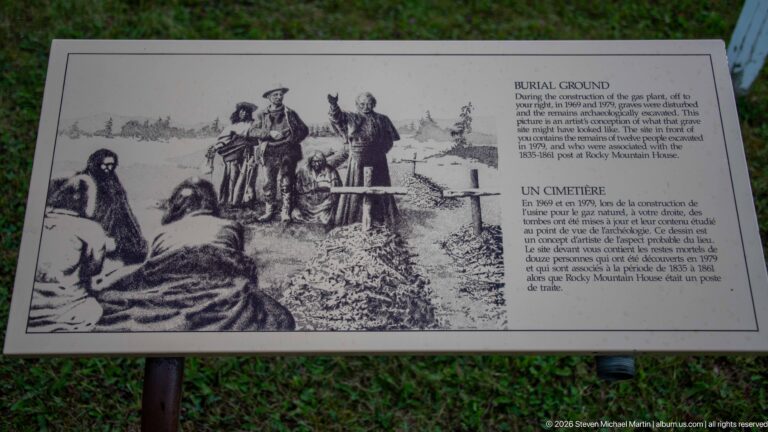 Outdoor 'Burial Ground' interpretive panel with a historical burial illustration and bilingual explanatory text.