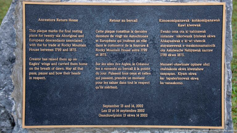 Dark memorial plaque with English, French, and Indigenous-language text marking the Rocky Mountain House burial ground.