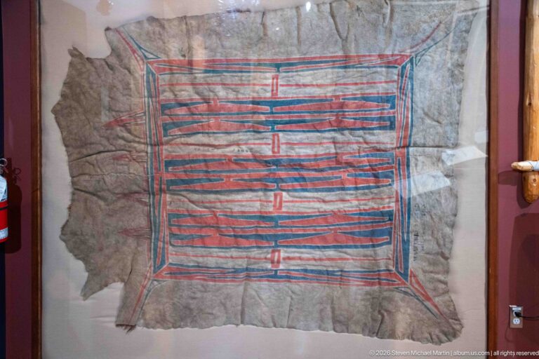 Large hide behind glass painted with a symmetrical rectangular pattern of red and blue parallel lines.
