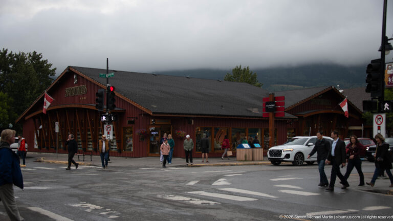 Visitors cross an intersection beside the Stonewaters Home storefront and its Canadian flag.