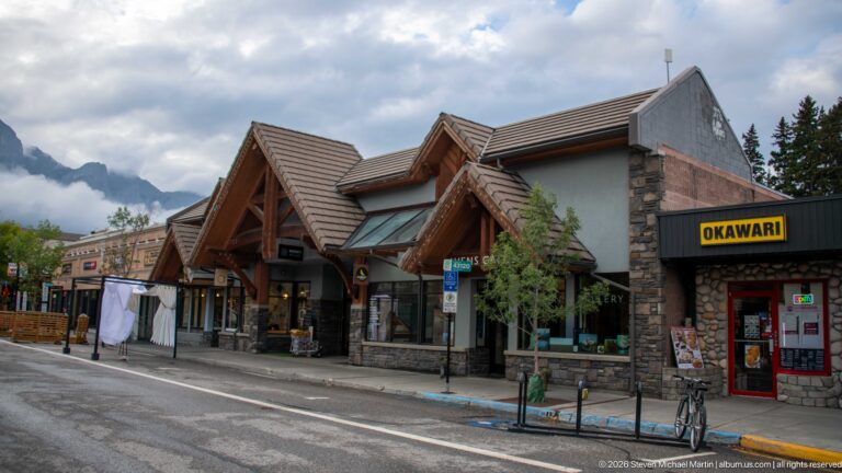 The Okawari storefront sits beneath overlapping timber gables and stone-clad commercial walls.