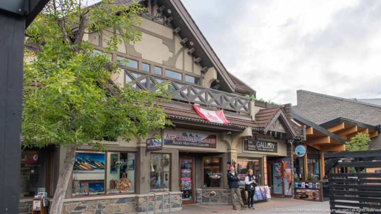 Art Country Canada’s storefront displays mountain and wildlife artwork beneath timber gables.