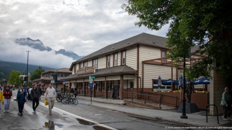 Visitors pass the Canmore Hotel’s covered veranda and side patio on a damp street.