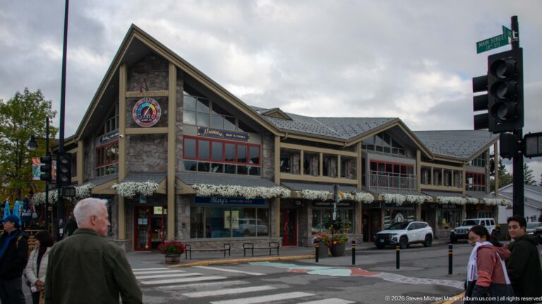 A stone-clad corner block with gabled roofs, flower boxes, and red-trimmed windows.
