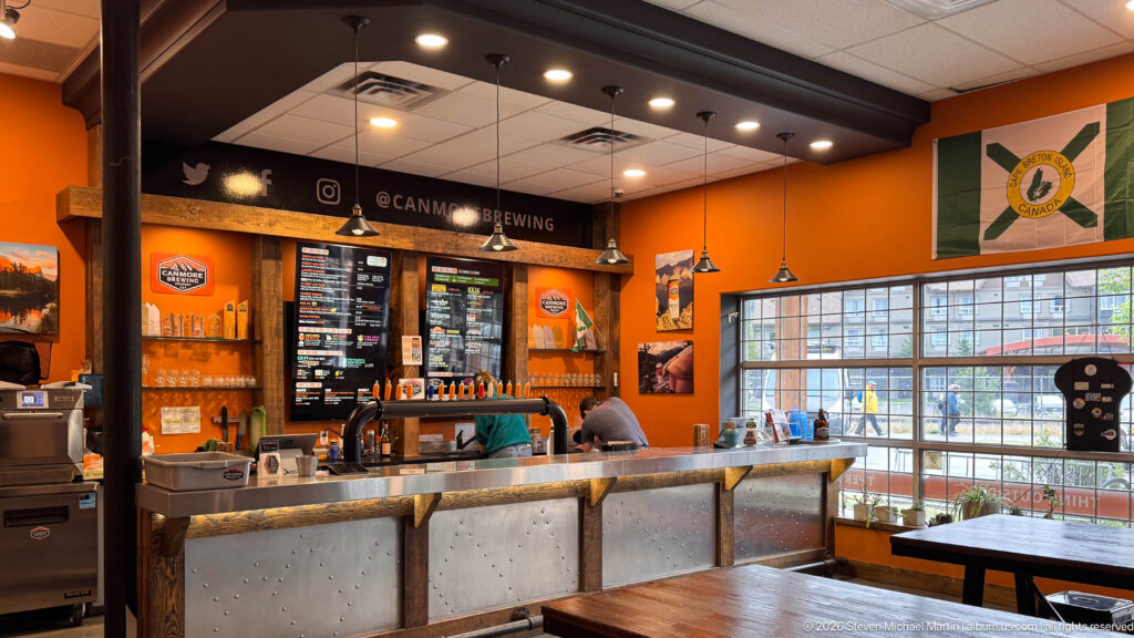 A stainless service bar with taps and menu boards anchors the orange Canmore Brewing taproom.