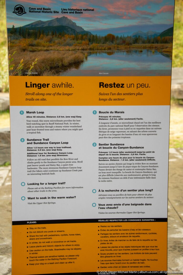 Trail information panel with a mountain panorama, bilingual heading, and route descriptions in two columns.