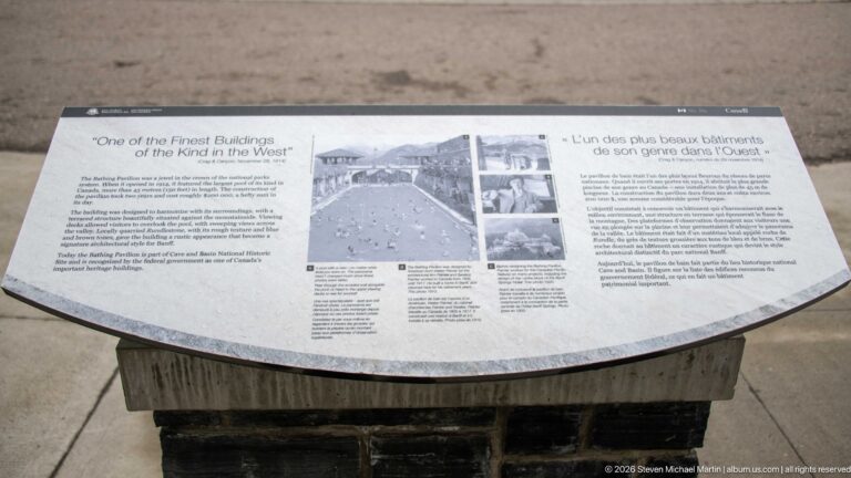 Curved bilingual heritage panel with archival photographs and text about a historically notable building.