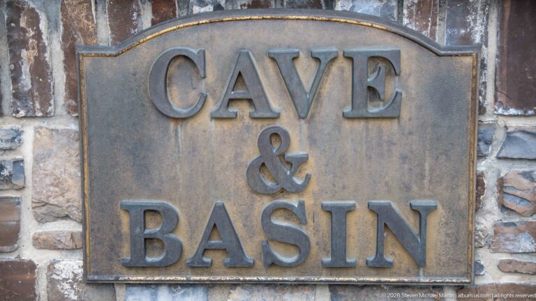 Raised CAVE & BASIN lettering appears on a bronze-colored plaque mounted on stone masonry.