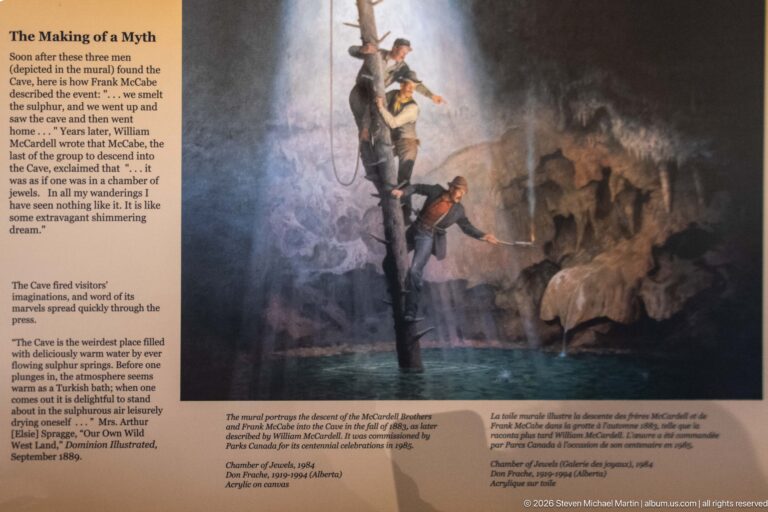 Bilingual text and a quotation accompany a mural of men entering the cave by rope.