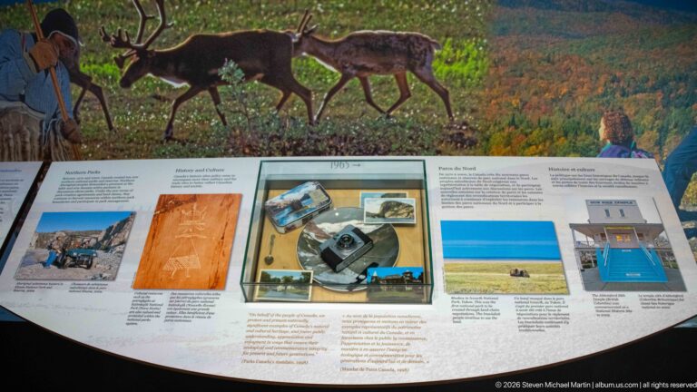 Two dark antlered wildlife figures stand above a curved park-history exhibit panel.