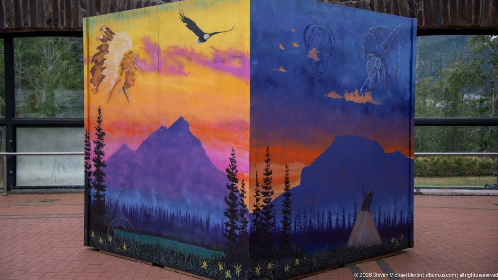 A painted courtyard cube shows mountain silhouettes, wildlife, and camp imagery in vivid colors.