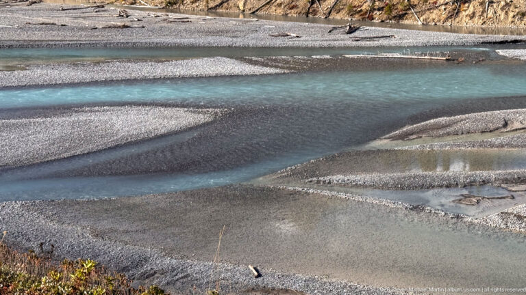 Narrow turquoise streams weave around smooth gray gravel bars and shallow pools.