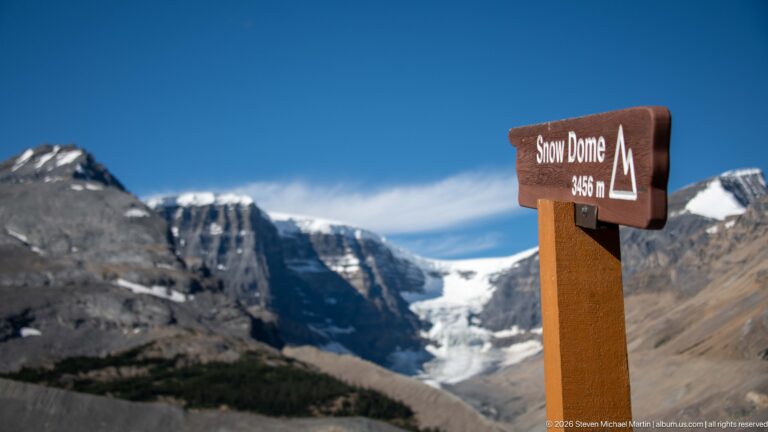 A brown sign reading “Snow Dome 3450 m” stands before a glacier and high peaks.