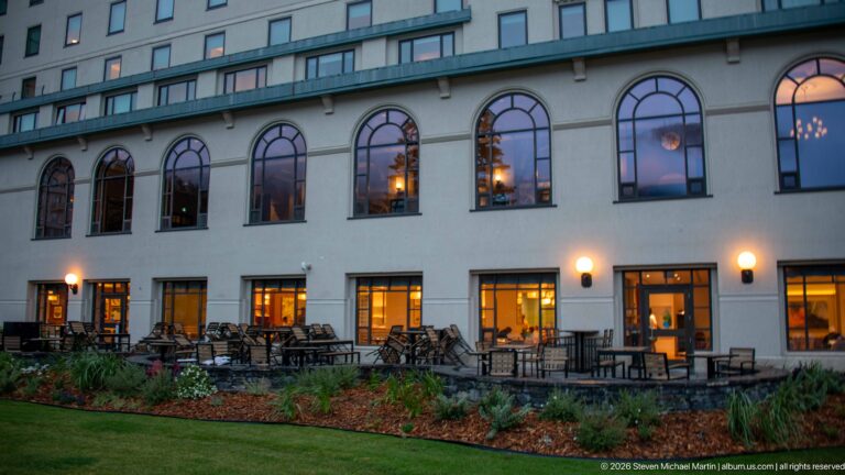 Repeated arched windows rise above an outdoor terrace at the Fairmont Chateau Lake Louise at dusk.