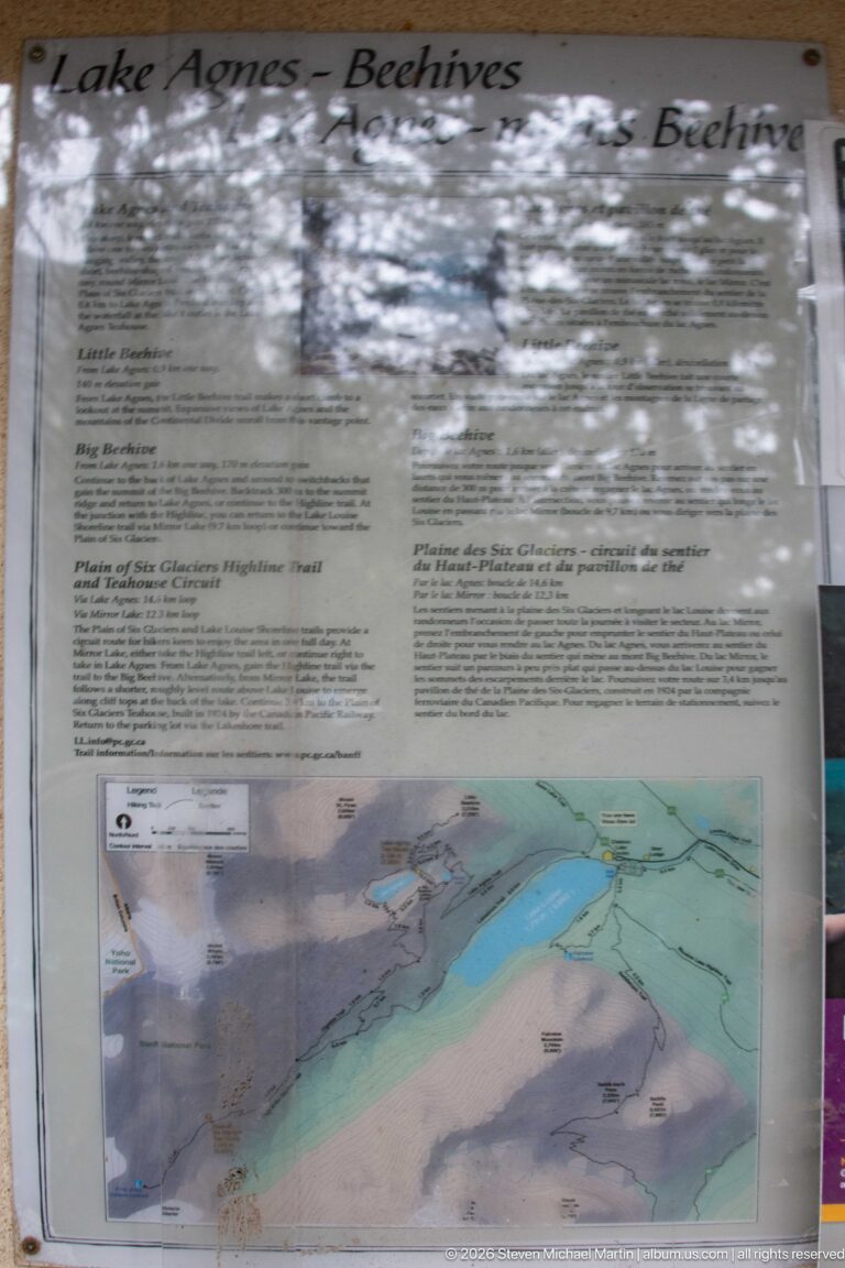 A reflective interpretive panel shows a map and trail information about the Beehives near Lake Louise.