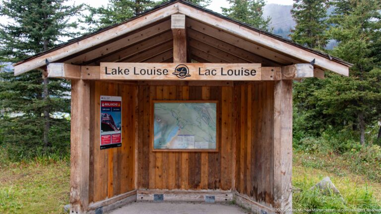 A timber kiosk labeled Lake Louise / Lac Louise displays a framed map beneath a pitched roof.