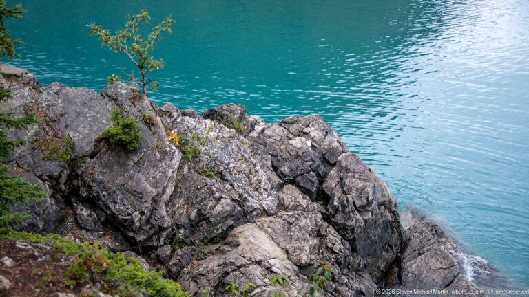Fractured pale shoreline rock beside vivid turquoise water at Lake Minnewanka.